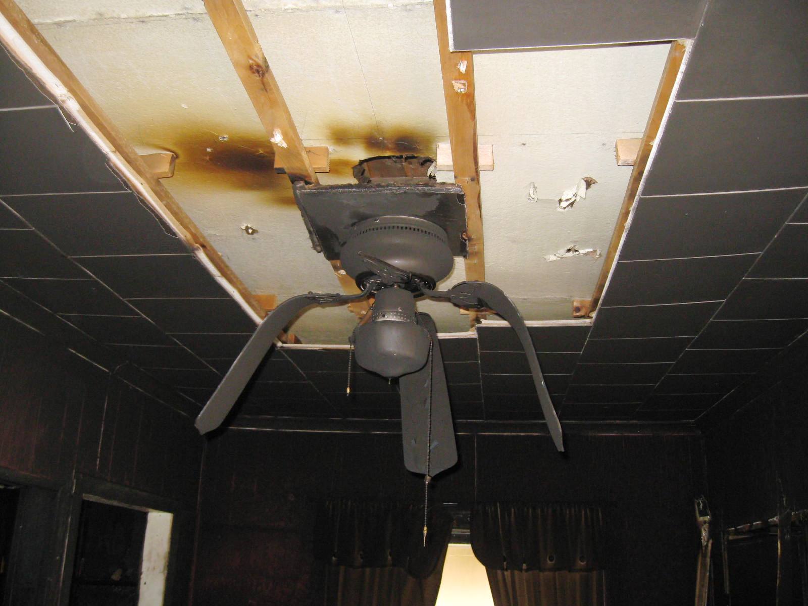 Ceiling fan drooping after being melted by a fire, smoke and fire damage throughout the ceiling.